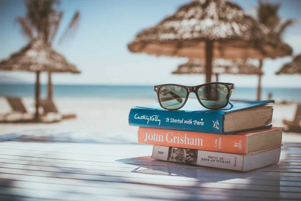 Bücher und Sonnenbrille am Strand. Babymoon, Urlaub in der Schwangerschaft | pregfit